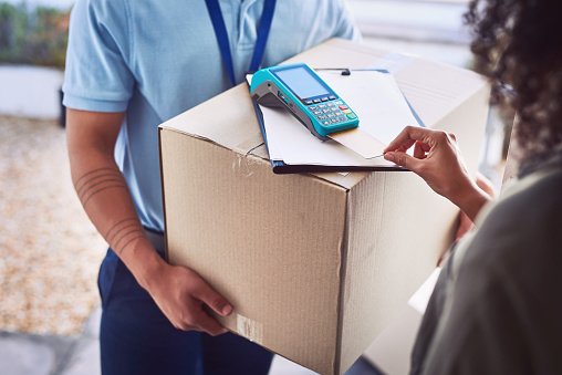Closeup shot of an unrecognisable woman using a credit card to pay for her delivery from the courier